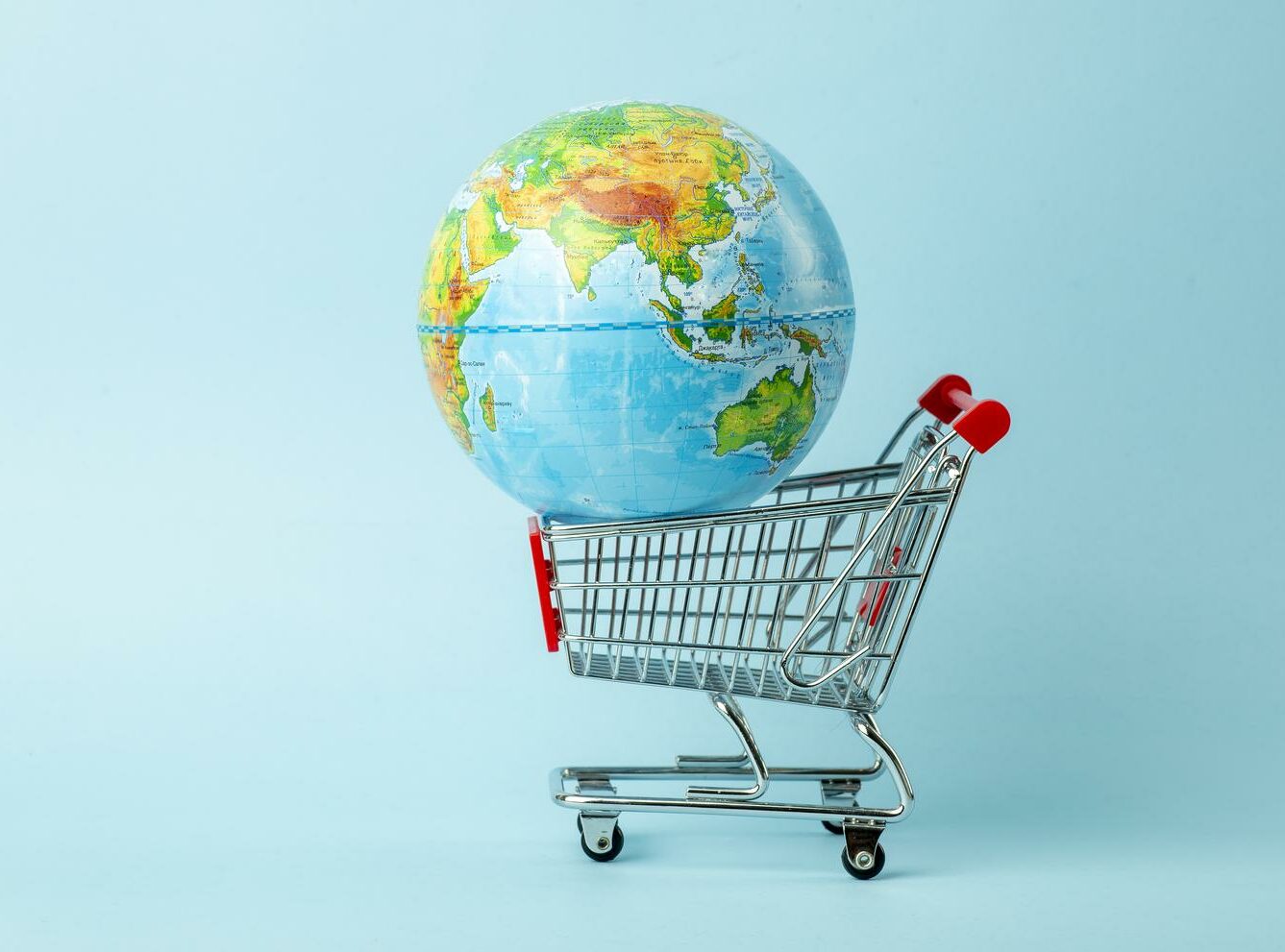 World sale and Internet sales concept. Supermarket cart with earth globe on blue background. World trade and delivery of purchases.