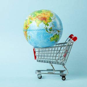 World sale and Internet sales concept. Supermarket cart with earth globe on blue background. World trade and delivery of purchases.