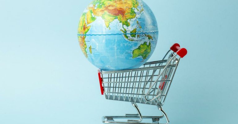 World sale and Internet sales concept. Supermarket cart with earth globe on blue background. World trade and delivery of purchases.